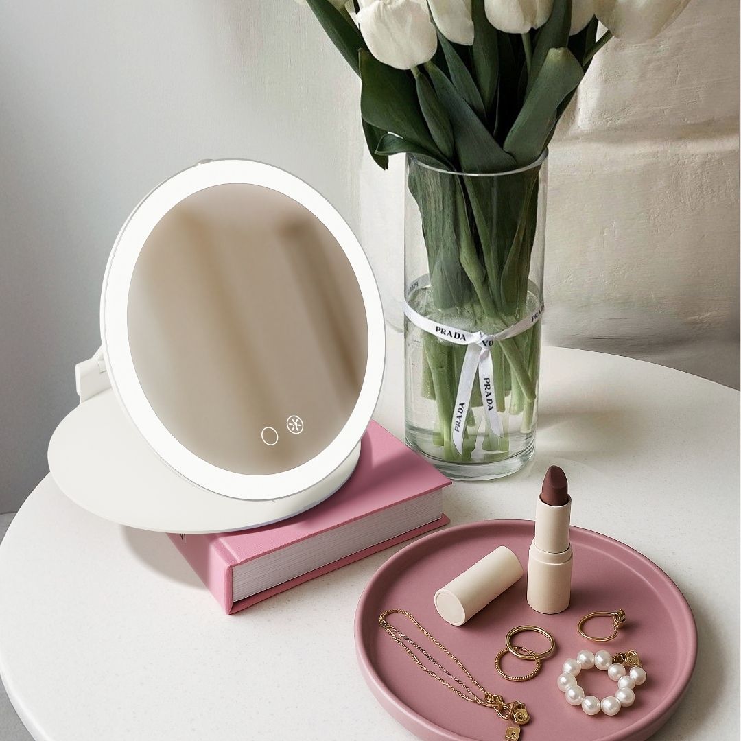 Abigail 10x magnification travel mirror with LED ring light on a white vanity with makeup accessories.