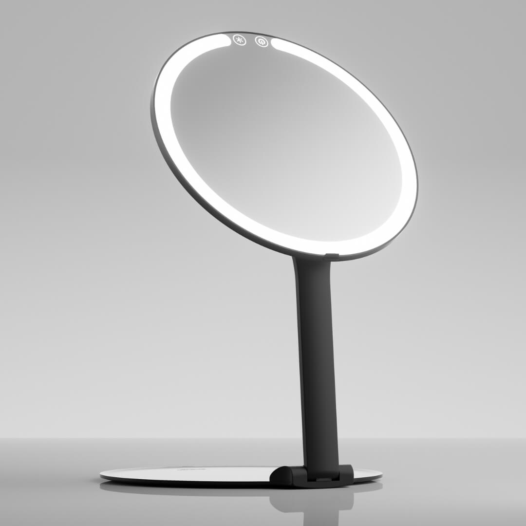 Abigail black LED travel makeup mirror with illuminated ring light and adjustable stand on a reflective surface.