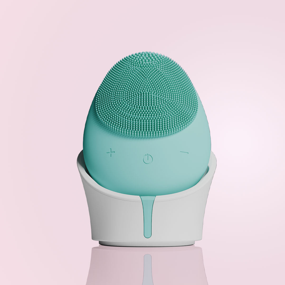 Isla mint green silicone sonic facial cleansing brush with 1600 bristles in a white charging base.
