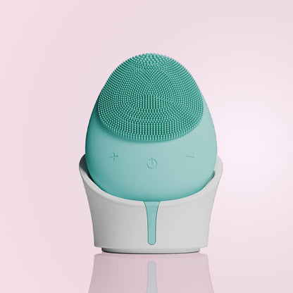 Isla mint green silicone sonic facial cleansing brush with 1600 bristles in a white charging base.