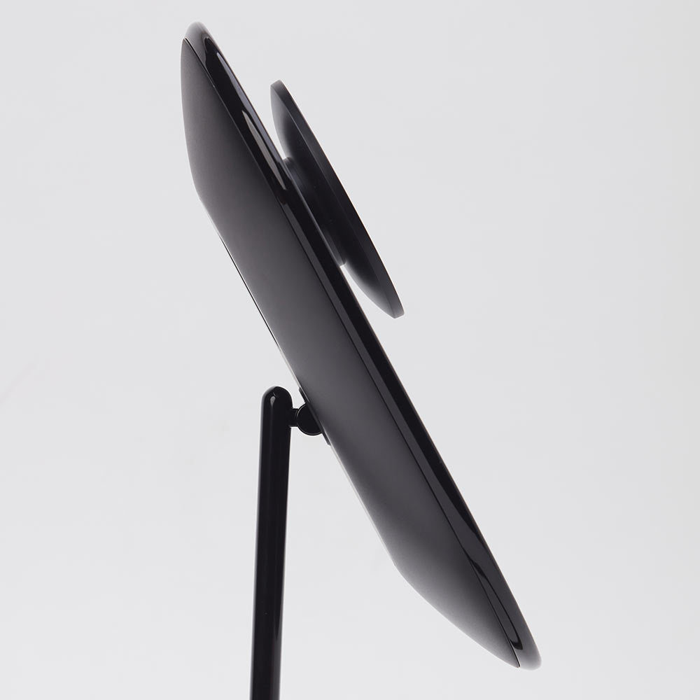 Side view of the Lara 10x magnifying mirror magnetically attached to the back of the black Vera vanity mirror.