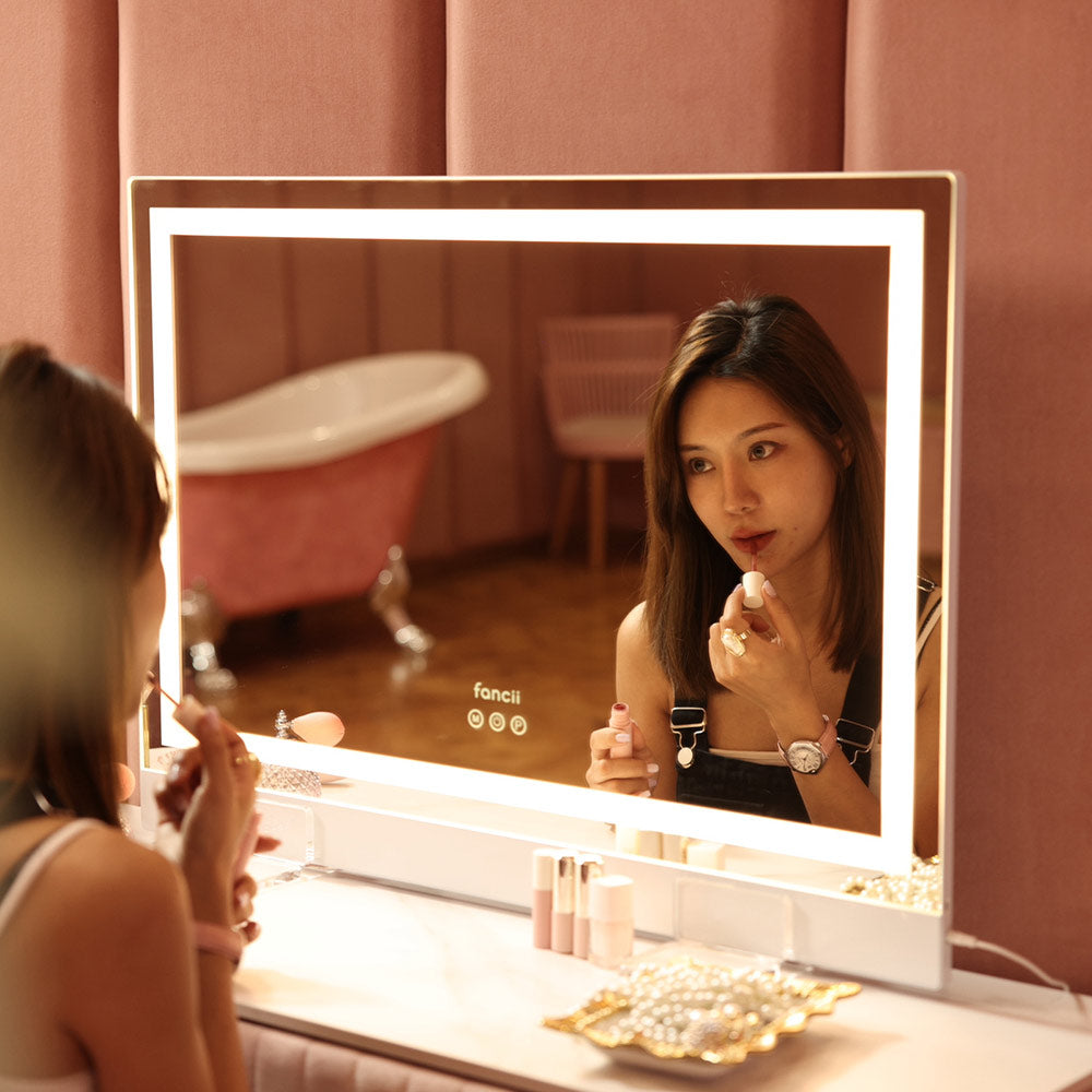 Woman using Monroe Hollywood Vanity Mirror with Omni-Glow LED lighting for professional makeup application.