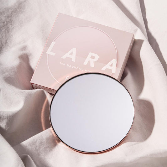Lara 10x Magnifying Mirror with pink magnetic attachment packaging on neutral fabric background.