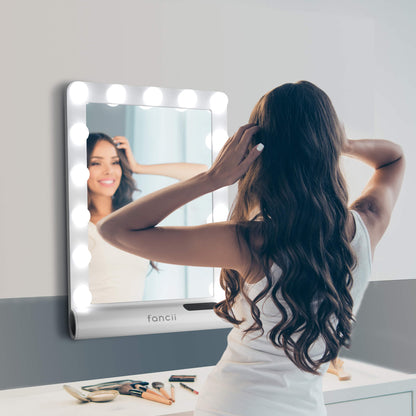 Madeline Mini Hollywood Mirror with LED bulbs and Bluetooth speaker, used for makeup and hair styling at a vanity desk.