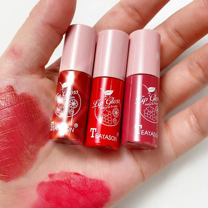 Three shades of LuxeGloss high-shine waterproof lip gloss in red and pink with swatches on a hand.