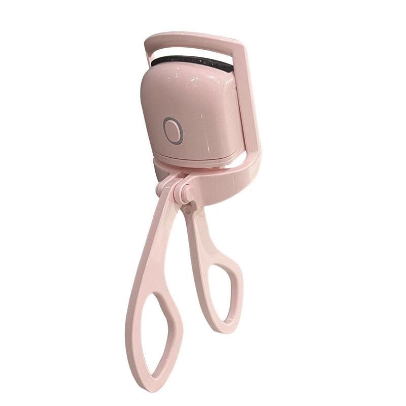 Pink LashWave electric eyelash curler with USB rechargeable power button and heated silicone pad on white background.