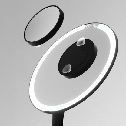 Tara 10x Magnifying Suction Mirror with black frame shown attaching to a larger illuminated LED vanity mirror.