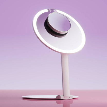 Abigail LED travel makeup mirror in white with light ring and 10x magnifying attachment on a pink surface.
