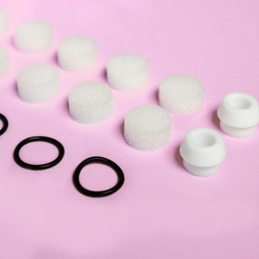 Clara Essential Kit replacement parts: white foam filters, black rubber rings, and silicone tips for pore cleanser.