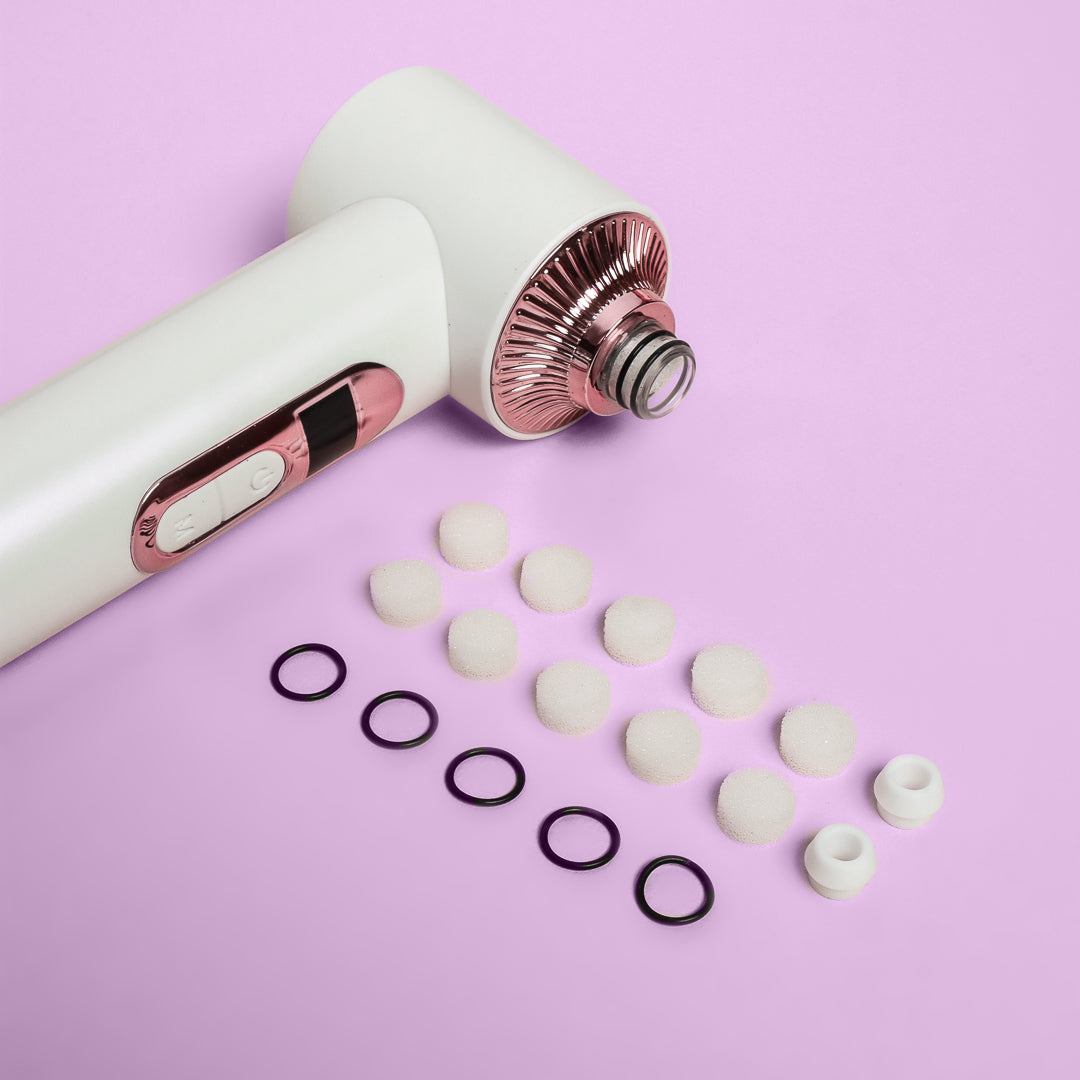 Clara Essential Kit replacement filters, rubber rings, and silicone tips for 4-in-1 Pore Cleanser on pink background.