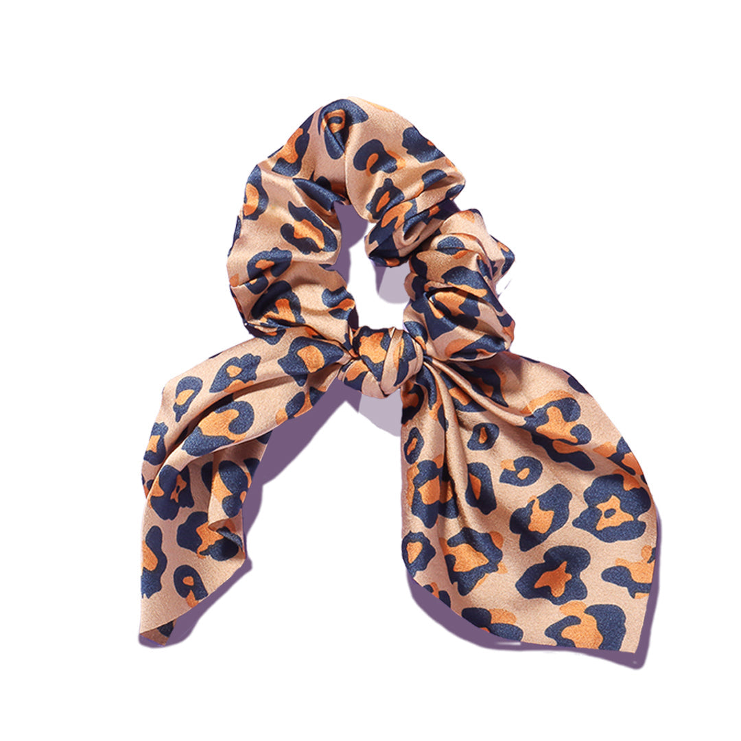 Elle leopard print satin scrunchie with chic bow detail on a white background, featuring tan and black animal spots.